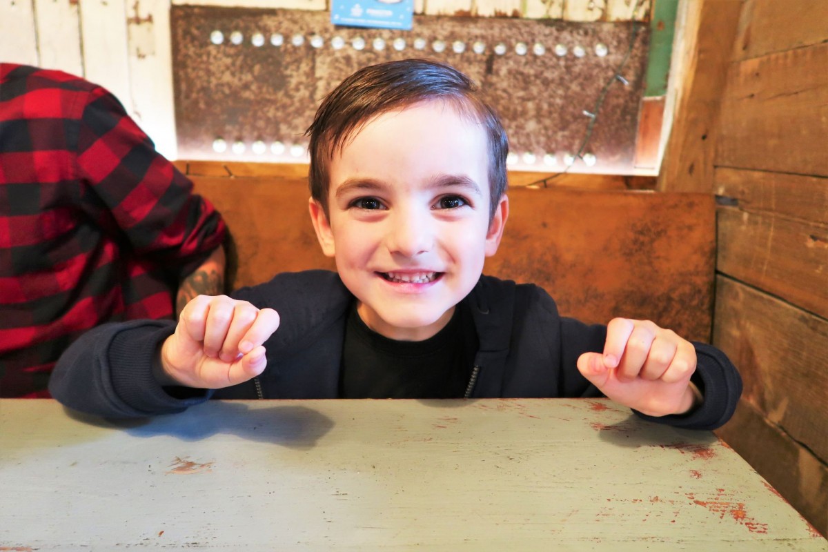 The Queens Head photo of a young child sitting at the table, his hands are clenched in fits whilst happily waiting for his dinner